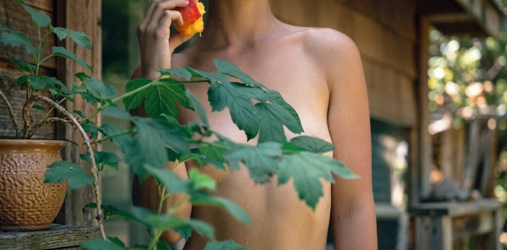 Adult woman eating a peach among fig leaves for an areola brightening guide
